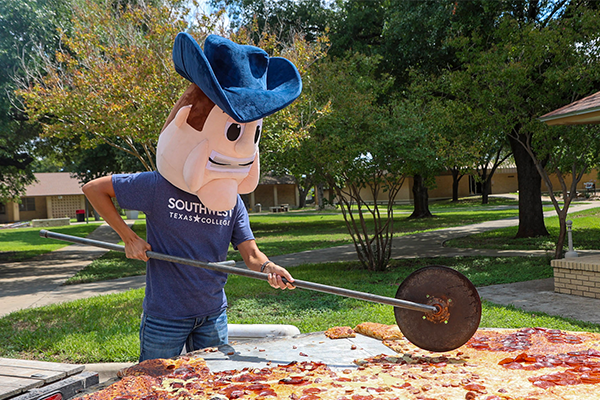 Student Employment - SWTX Mascot Tex slices pizza for students at a campus event.