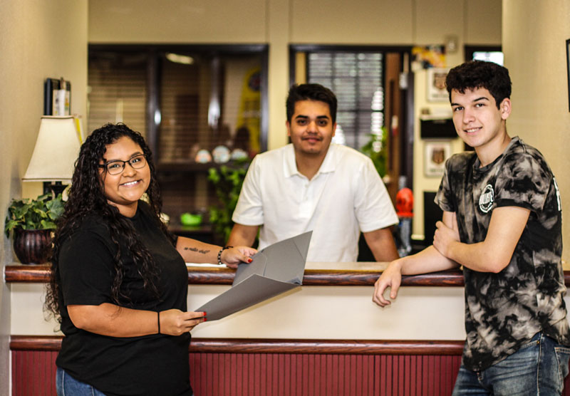 Three students reviewing papers with clerk at counter