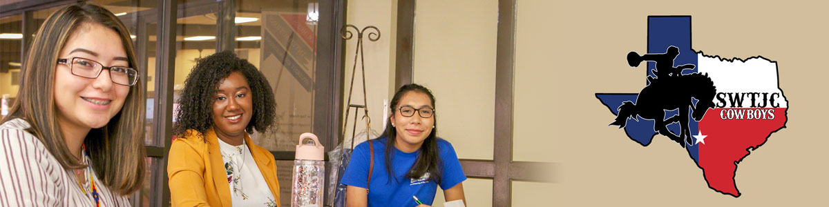 Three students sit at a table smiling at camera